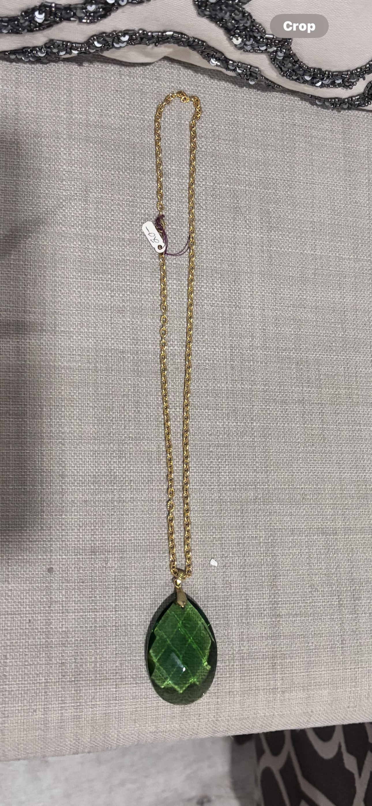 Faceted green teardrop glass pendant set on a gold-tone chain