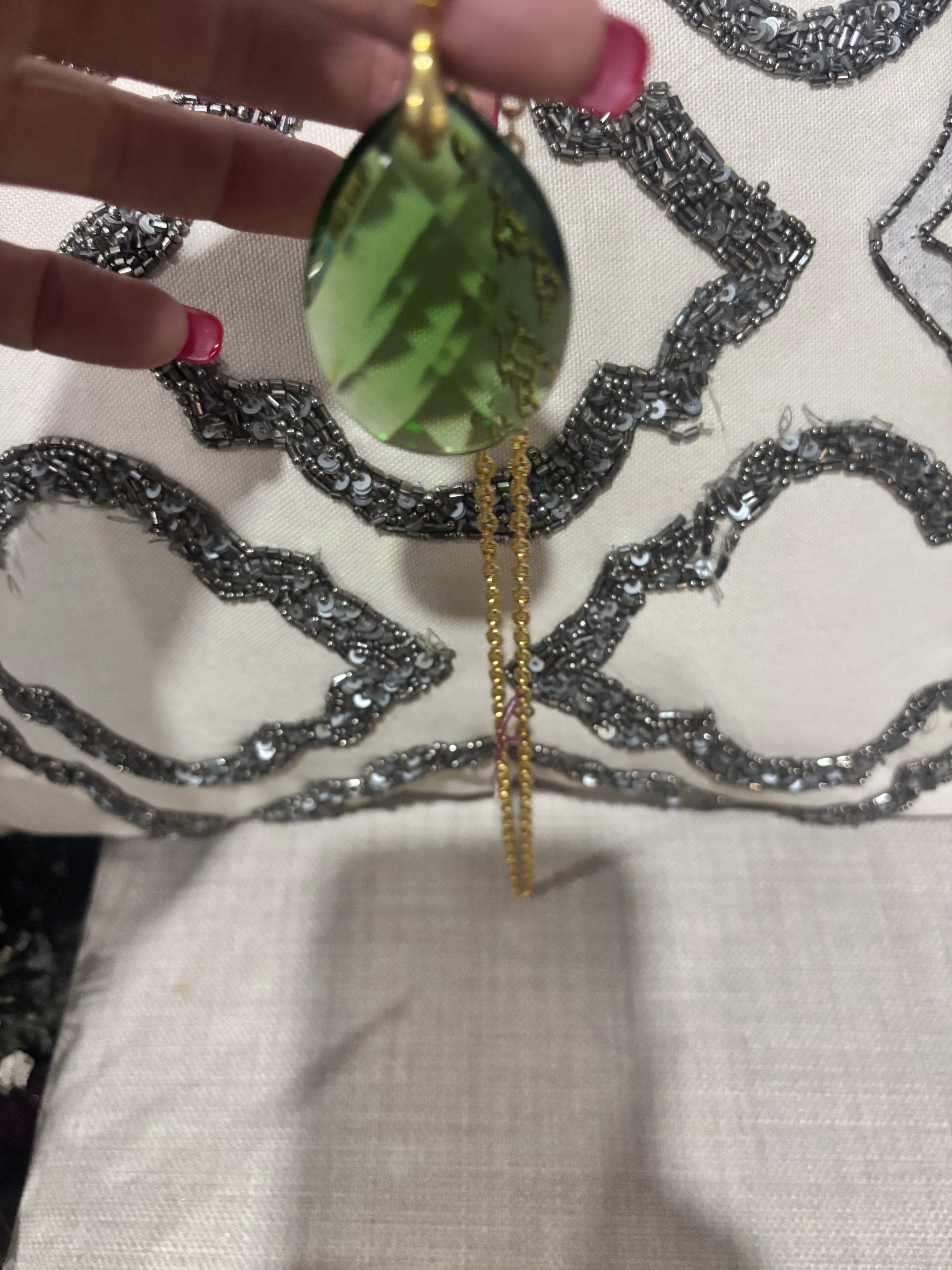 Faceted green teardrop glass pendant set on a gold-tone chain